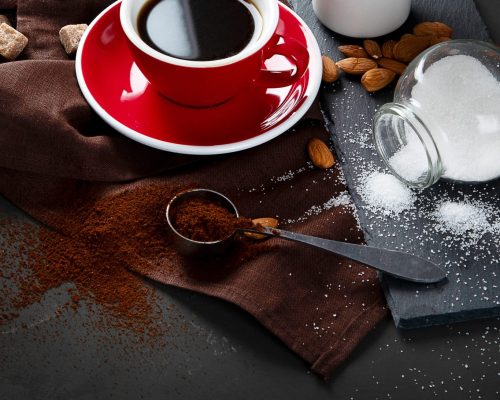 Red coffee cup and beans on dark  table. Top view with copy space